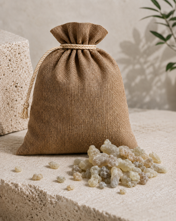 A small natural burlap drawstring pouch sits on a textured stone surface with Hojari Boswellia Sacra spilled in front of it. This shows 1KG size of premium resin. 