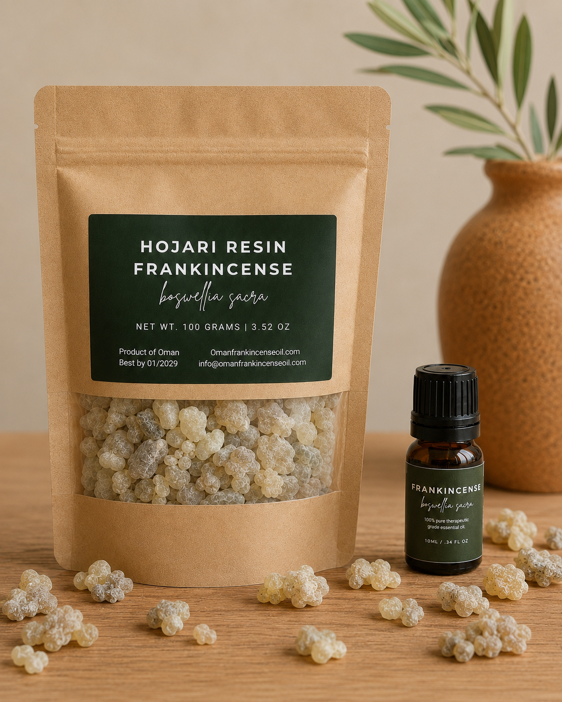 A kraft paper pouch labeled 'Hojari Resin Frankincense' with a clear window showing dried resin pieces, alongside a small dark amber bottle with a black cap. The products are arranged on a wooden surface with scattered resin pieces in front and a ceramic vase with greenery in the background.