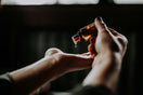 Hand pouring Premium Omani Hojari Frankincense Essential Oil (Boswellia sacra) from a bottle, steam distilled from authentic frankincense resin harvested in Dhofar, Oman.