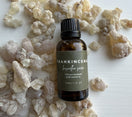 30 ml bottle of Premium Omani Hojari Frankincense Essential Oil resting on authentic Boswellia sacra frankincense resin harvested in Dhofar, Oman.