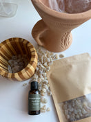 Bottle of Premium Omani Hojari Frankincense Essential Oil displayed with authentic Boswellia sacra frankincense resin and a traditional incense burner used to burn frankincense from Dhofar, Oman.
